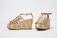 Pair of off-white platform sandals with latticework vamp and gold metal cherub heads on platfor…