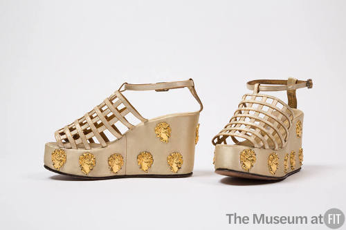 Pair of off-white platform sandals with latticework vamp and gold metal cherub heads on platfor…