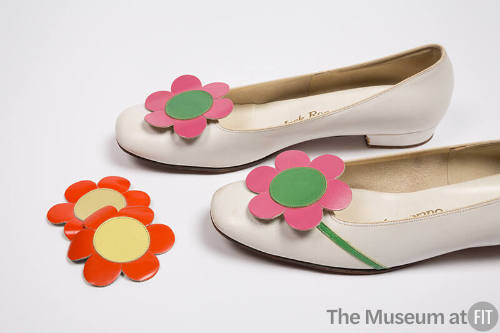 Pair of white low heel pumps with large pink flower and green center on round toe and alternate…