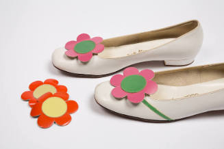 Pair of white low heel pumps with large pink flower and green center on round toe and alternate…