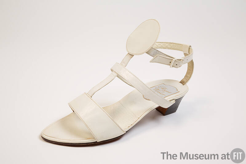 White T strap sandals with T extending to ankle strap with large round center circle, black lea…
