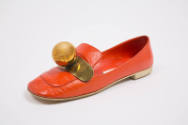 Orange leather slip on flat with flat white heel and brass plaque with large brass ball and bel…
