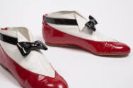 Pair of red patent leather ankle boots with white and black uppers to mimic a man’s tuxedo