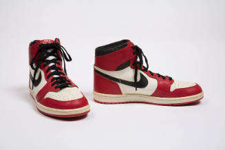 Pair of red, white, and black man’s high top sneakers with black Nike swoosh logo on the side