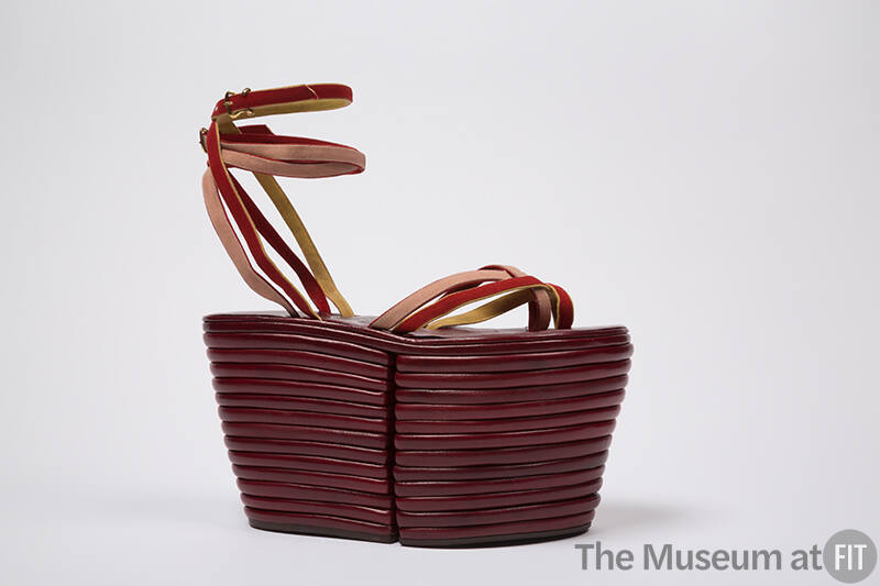 Dark red sandal with extremely high platform and red, yellow and pink tie straps across vamp an…