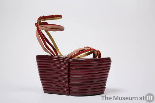 Dark red sandal with extremely high platform and red, yellow and pink tie straps across vamp an…