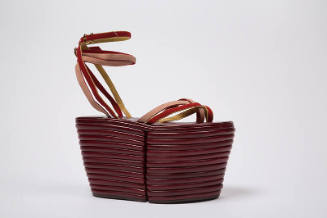 Dark red sandal with extremely high platform and red, yellow and pink tie straps across vamp an…