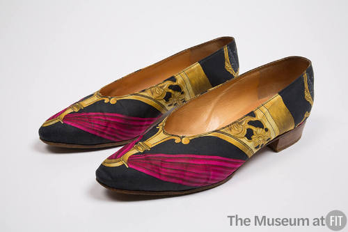 Pair of printed flat shoes with yellow architectural motifs and red drapery on black ground