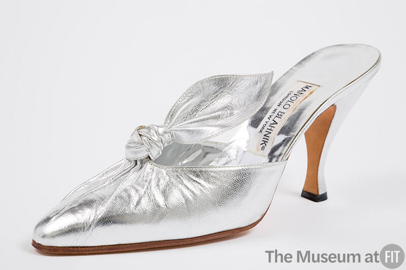 Silver mule shoe with pleated vamp extending to knotted tab, pointed toe and high Louis heel