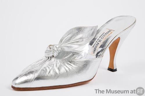 Silver mule shoe with pleated vamp extending to knotted tab, pointed toe and high Louis heel