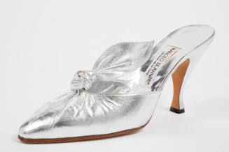 Silver mule shoe with pleated vamp extending to knotted tab, pointed toe and high Louis heel