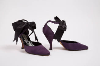 Pair of purple d'Orsay shoes with high heels and large black satin bow at ankle strap