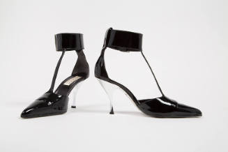 Black T strap shoes with pointed toe, wide buckled ankle strap, and silver high heel
