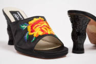 Detail view of black mules showing embroidered yellow and orange rose with blue, green and whit…