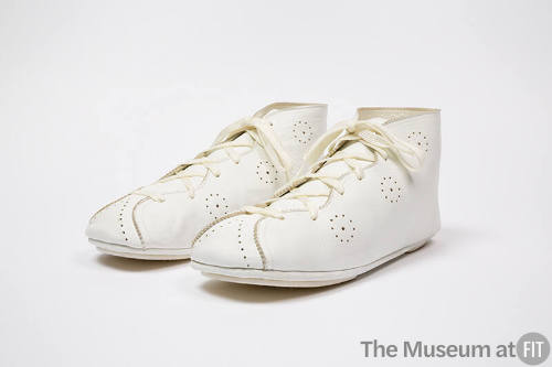 Pair of white lace up ankle boots with perforations throughout and flat sole
