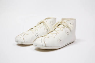 Pair of white lace up ankle boots with perforations throughout and flat sole
