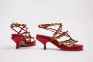 Pair of red thong sandals with narrow vamp straps and wrap around ankle strap trimmed with rose…