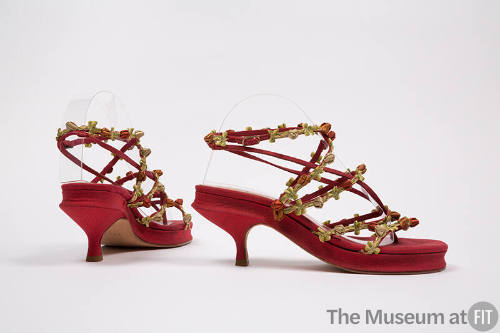 Pair of red thong sandals with narrow vamp straps and wrap around ankle strap trimmed with rose…