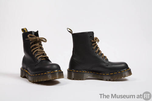 Black lace-up work boots with yellow stitching and  thick brown soles 