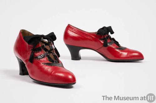 Red ghillies with black scalloped trim, loops and heel; ribbon ties