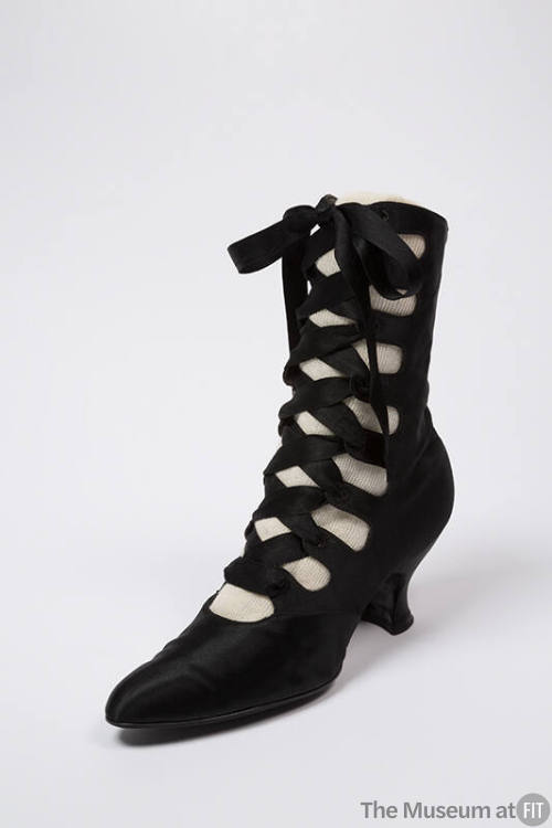 Black calf height boot with crisscrossing lace up front closure, slightly rounded pointed toe a…