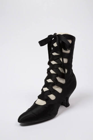 Black calf height boot with crisscrossing lace up front closure, slightly rounded pointed toe a…