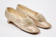 Pair of ivory court style shoes with large pleated rosette pom poms at top center, square toe a…