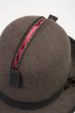 Detail view of man’s brown charcoal wool hat showing zippered compartment on crown open to reve…