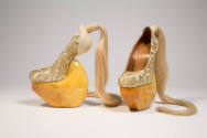 gold metallic lace over beige heel-less shoes with high wood platform and blond hair ponytail a…