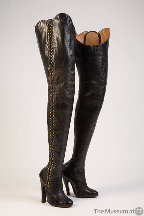 Black thigh high lace up high heel boots with brass hooks at outside leg
