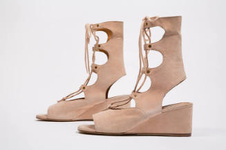 Pair of beige calf height lace up sandals with scalloped front, heel cut out and wedge heel