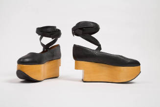 Pair of black shoes with wrap leg tie and wooden platform with curved front and heel cut out