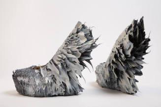 Pair of grey platform shoes covered in various growth-like protrusions facing outwards from pla…