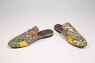 Alternate view of brown Gucci mules with bird motif mule on left and flower motif mule on right…