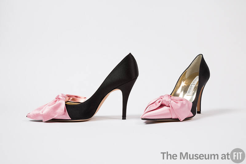 Pair of black high heel evening pumps with pink draped bow on vamp and pink pointed toe