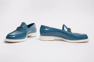 Pair of man’s blue rubber loafers with white sole and silver metal horsebit buckle across vamp