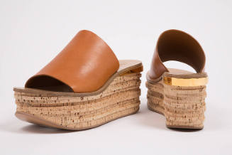 Pair of orange slide platform sandals with cork platform and gold band trim at heel