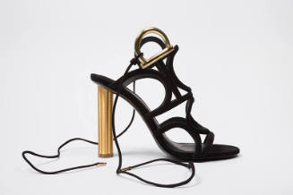 Black sandal with thin straps of linking circles, tie ankle straps attached by gold hardware an…