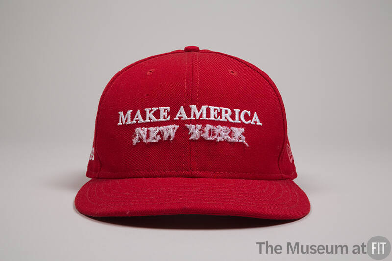 Red baseball cap with white embroidered text “Make America” and white dimensional embroidered “…