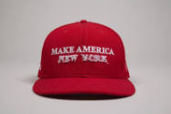 Red baseball cap with white embroidered text “Make America” and white dimensional embroidered “…