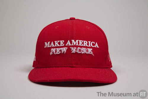 Red baseball cap with white embroidered text “Make America” and white dimensional embroidered “…