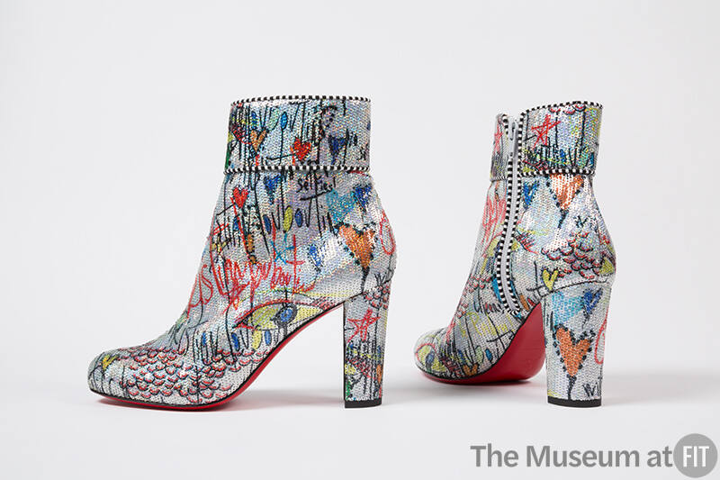 Pair of silver high heel ankle boots with allover black writing and multicolor graffiti-like de…