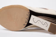 Detail view of bottom of sling back sandal showing designer’s Nicholas signature on sole