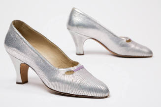 Pair of silver evening pumps with allover contrasting linear topstitching and eyelet cutouts at…