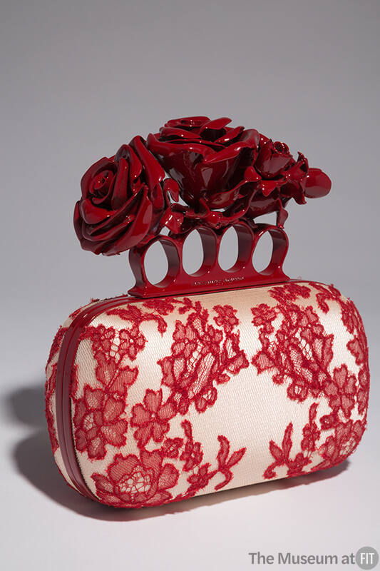 Off-white hand bag with red lace overaly, red metal knuckle handle with red roses