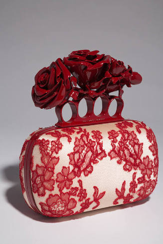 Off-white hand bag with red lace overaly, red metal knuckle handle with red roses