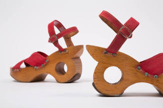 Pair of sandals with red elastic straps crossed at vamp and attached to wooden heel with silver…