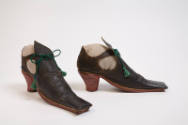 side view of long square toed black leather shoes; red heels, open sides; green tassel ties