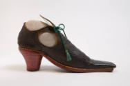 side view of long square toed black leather shoe; red heel, open sides; green tassel tie