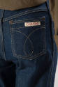 Back pocket of dark blue denim jeans with "Calvin Klein" label and brown contrast stitching